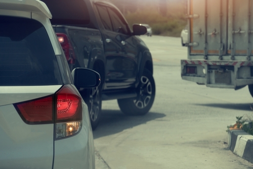Cars and a truck waiting on a curved road, with one vehicle’s brake lights illuminated.