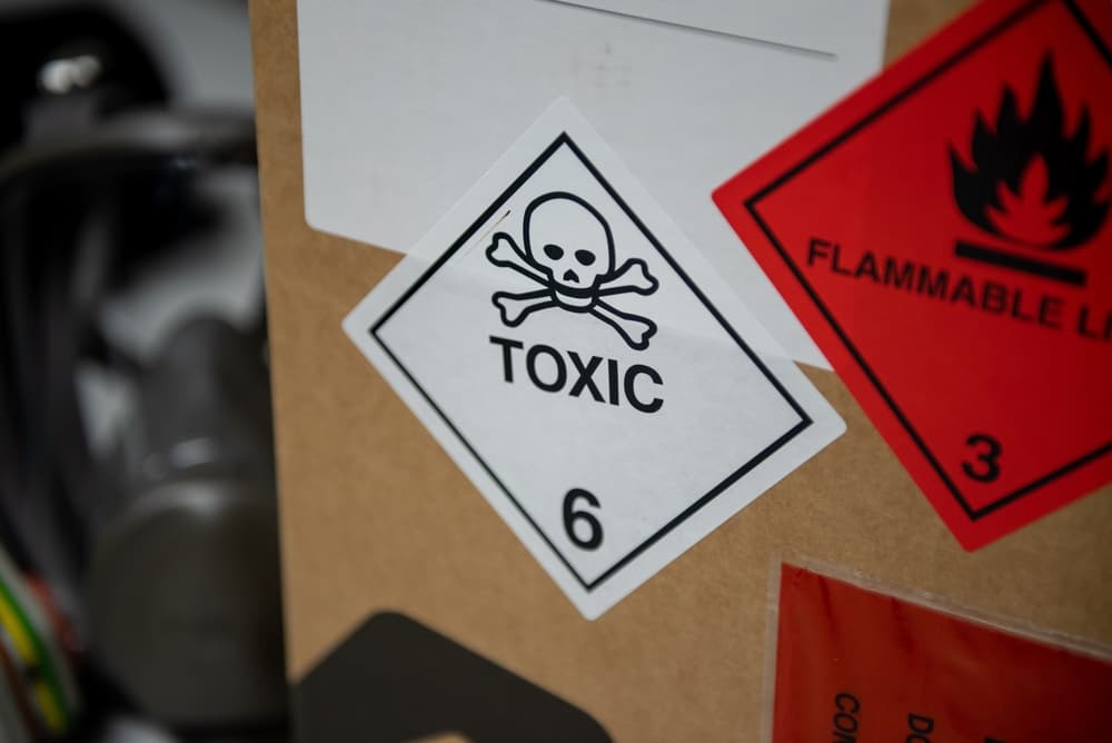 Image depicting a hazardous material symbol on a box, with a mask in the background, indicating potential danger.