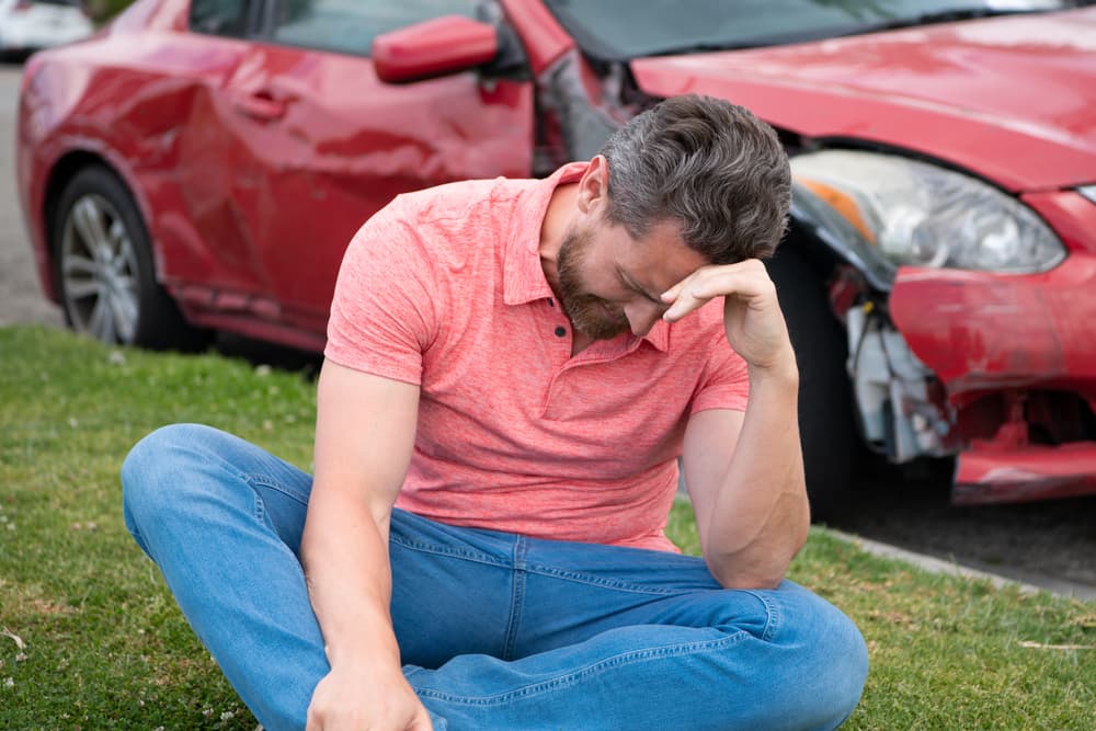 Upset driver sitting in front of his damaged car after the traffic accident in Newberry.