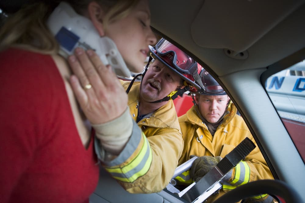 Emergency responders aiding injured woman in vehicle accident