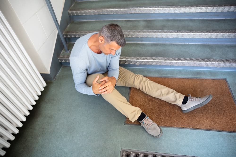 Image of an older man seated on stairs following a slip and fall accident.