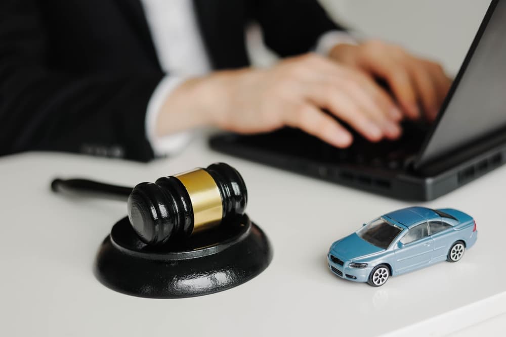 A skilled car accident lawyer equipped with a laptop, alongside a gavel symbolizing legal proceedings, navigates the complexities of liability insurance.