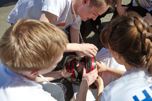  A group of people providing first aid to an injured person lying on the ground, carefully removing the individual's motorcycle helmet.