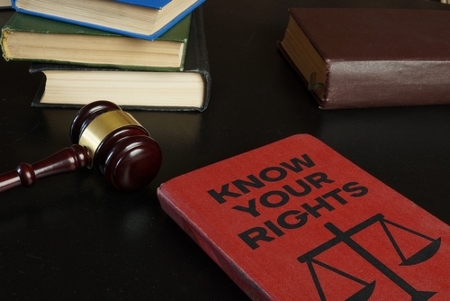 A legal-themed setup with a gavel, stacked books, and a red book titled "Know Your Rights" on a dark surface, emphasizing legal knowledge and rights.