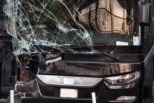 A damaged bus with a shattered windshield and severe front-end damage, indicating the aftermath of a bus accident.