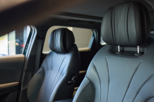 A close-up view of two black leather car seats with adjustable headrests inside a modern vehicle, highlighting the design and safety features.