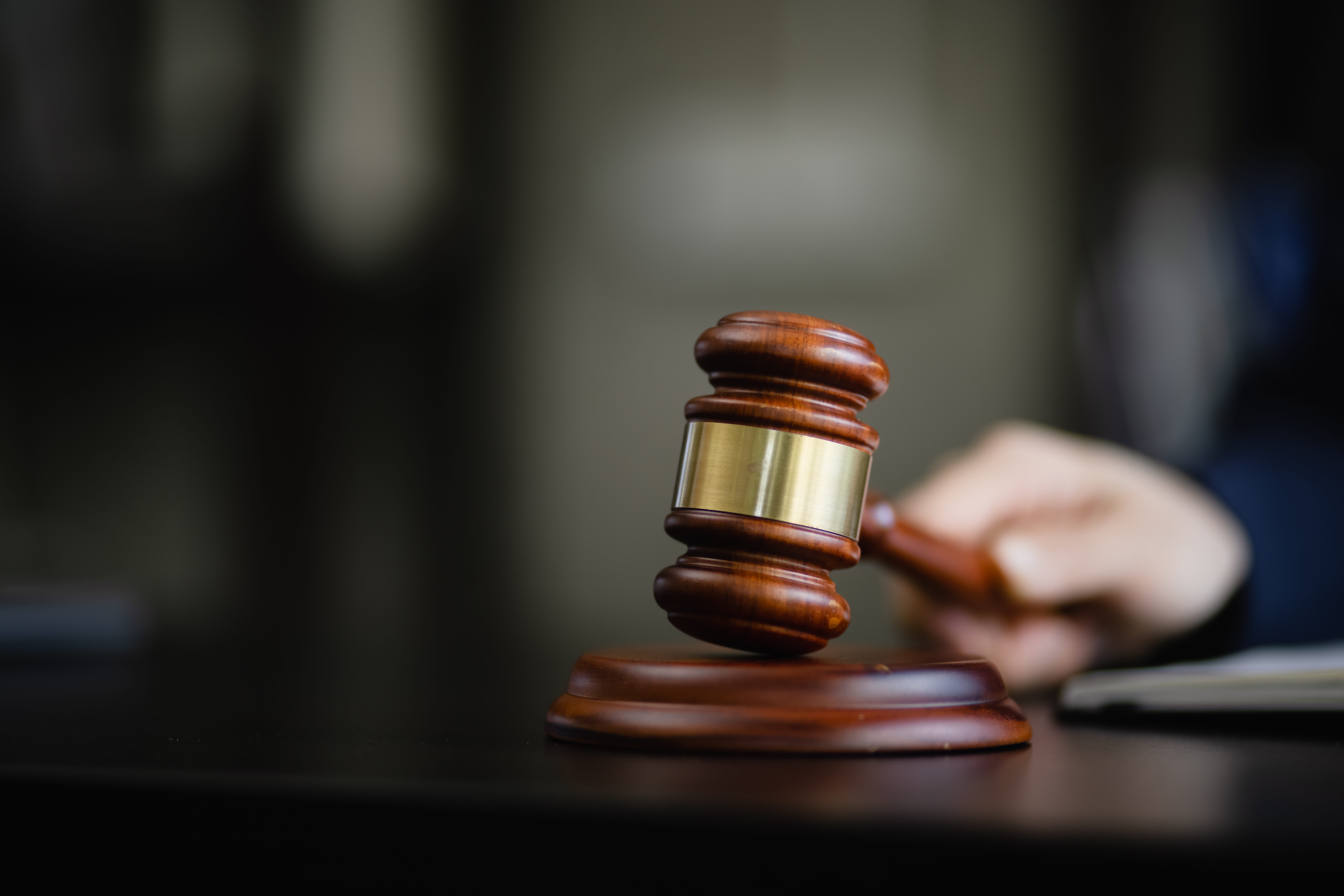a closeup of a judge's hand holding a gavel