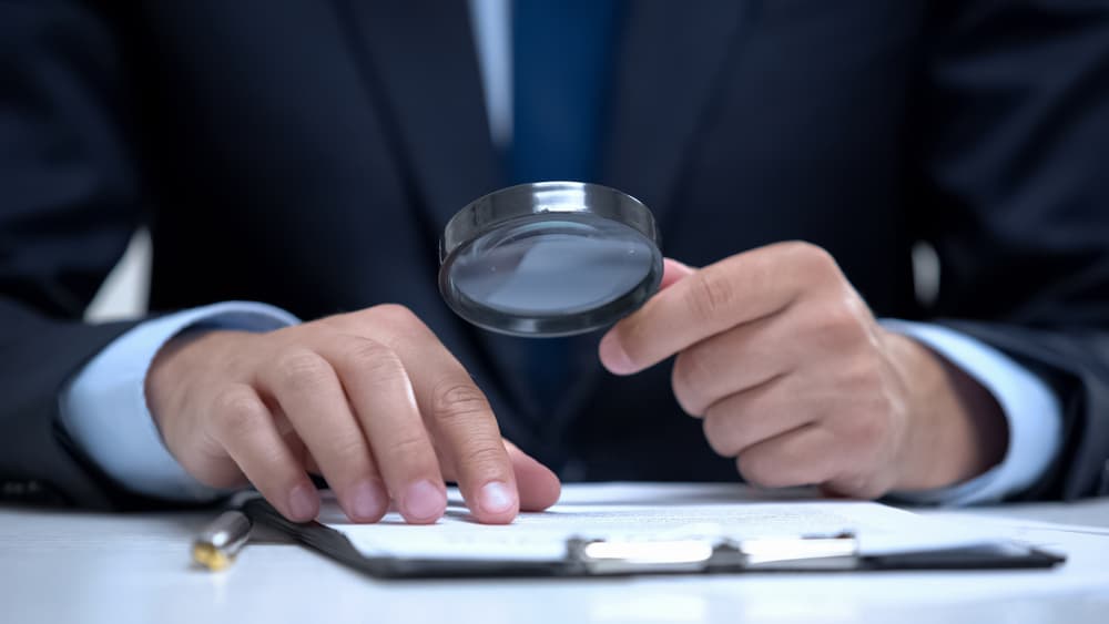 Attorney reading document with magnifier, studying case in detail, investigation