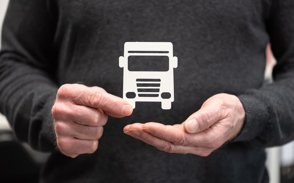 Man holding a paper truck; Concept of truck insurance