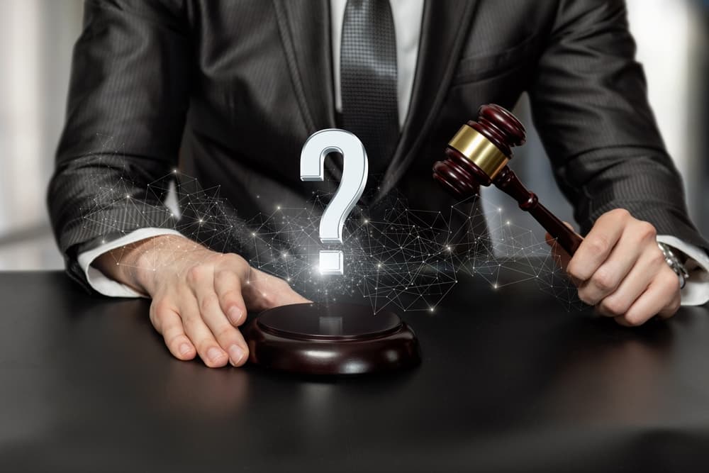 Personal injury lawyer gavel in hand and question mark sign