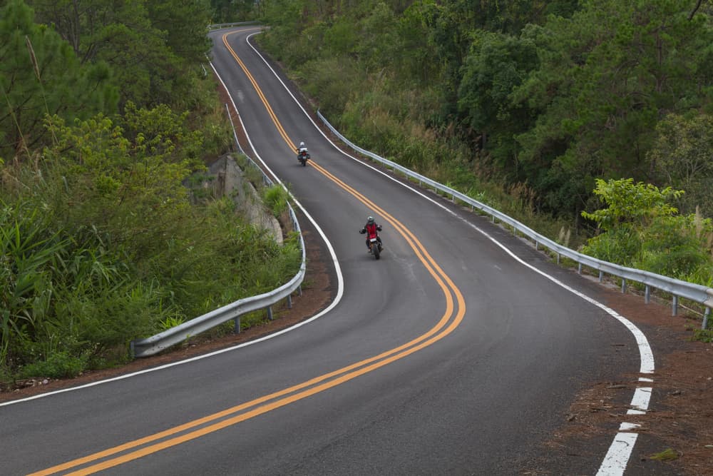 A biker on the road that worn out guardrails