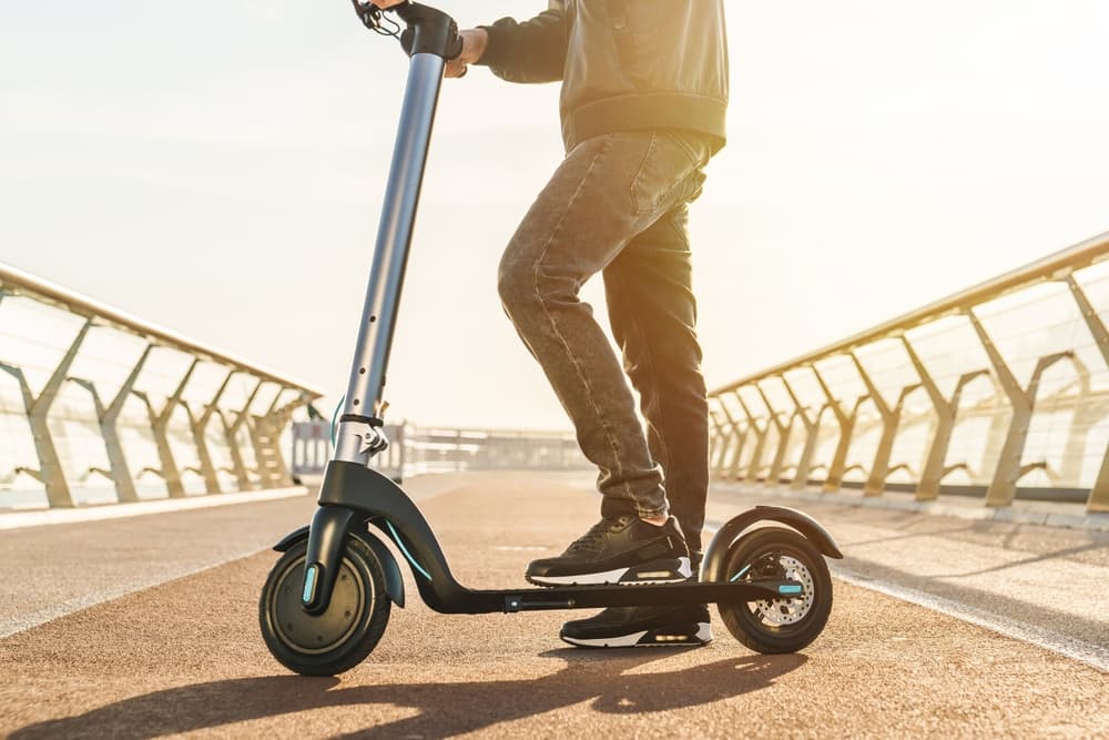 Man in stylish outfit stand on electric scooter on the street