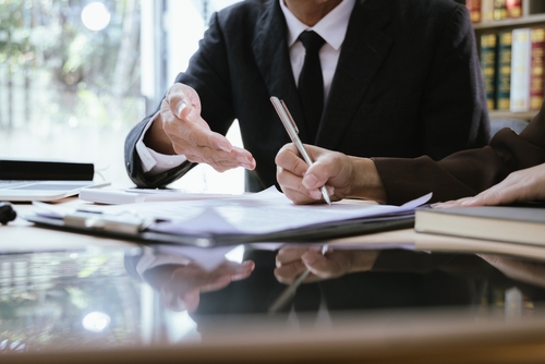 Lawyer discussing legal documents with a client at a desk.