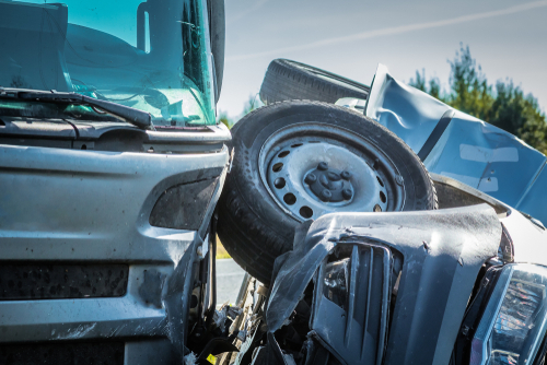 Close-up of a car and truck collision showing the front of both vehicles damaged.