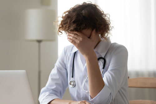 A distressed female doctor covering her face with her hand, representing medical error or emotional strain related to a wrongful death case.