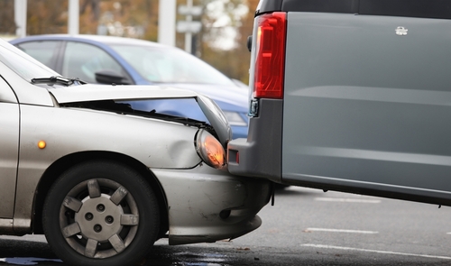 A rear-end collision between two vehicles, showing the front of one car damaged against the back of a van.
