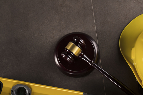 Wooden gavel beside a yellow hard hat and level on a dark surface, symbolizing construction accident legal cases in Gainesville.