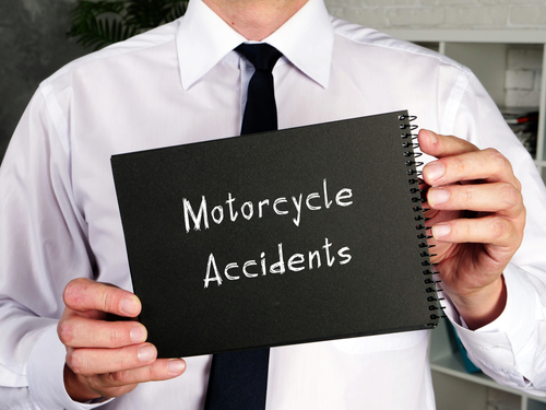 A man holding a notebook with the words "Motorcycle Accidents" written on the cover.