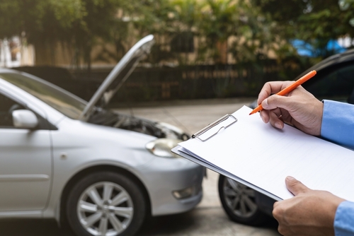 An insurance adjuster inspecting two crashed cars with a clipboard, illustrating claims managed with the support of a Gainesville car accident lawyer.