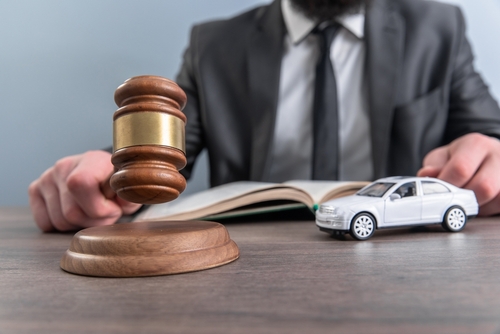 A lawyer reviewing a legal file beside a gavel and a model car, representing the work of a Gainesville car accident lawyer building an injury case.