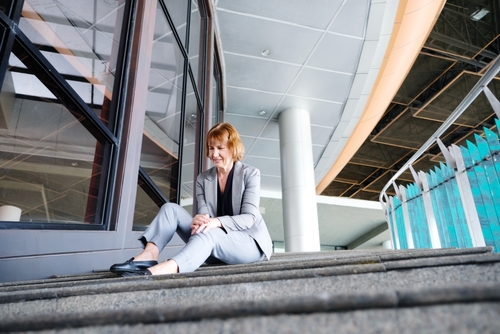 Woman sitting on outdoor steps after a fall at a commercial building, a situation often clarified through Daytona store surveillance footage.