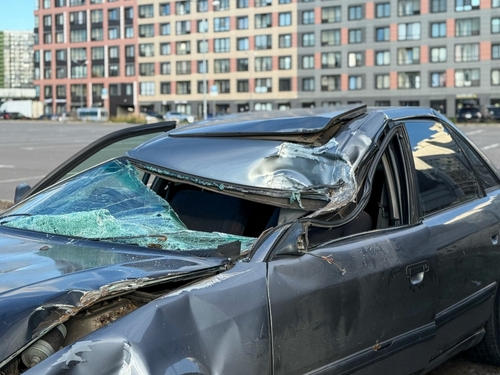 Wrecked sedan with a crushed roof and shattered windshield in a parking lot, representing cases handled by a Gainesville car accident lawyer involving severe vehicle damage.
