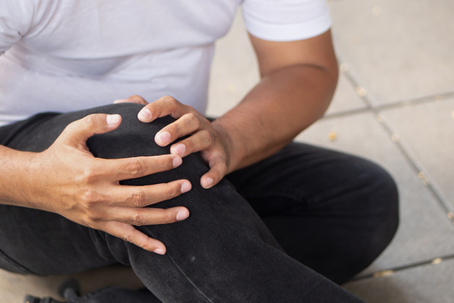 Person sitting on pavement holding injured knee after a fall, representing injury claim handled by a Gainesville slip and fall accident lawyer.