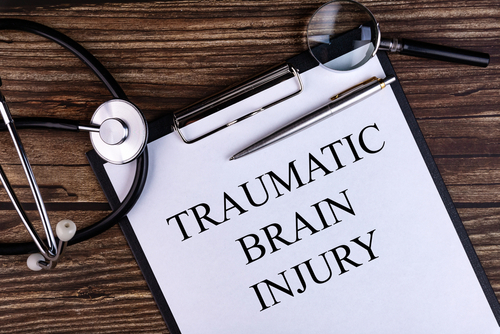 Clipboard labeled traumatic brain injury with stethoscope and magnifying glass, symbolizing legal representation by an Ocala traumatic brain injury lawyer.