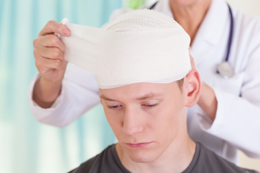 Doctor wrapping head bandage on injured patient, representing medical treatment in a case handled by an Ocala traumatic brain injury lawyer.