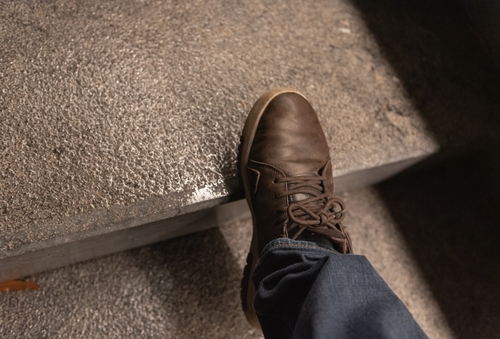 Close-up of shoe slipping on wet concrete step, illustrating hazard investigated by a Daytona Premises Liability Accident Lawyer.