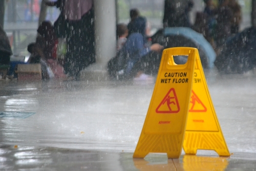 Caution wet floor signs during heavy rain in public area, example of case handled by a Daytona Premises Liability Accident Lawyer.