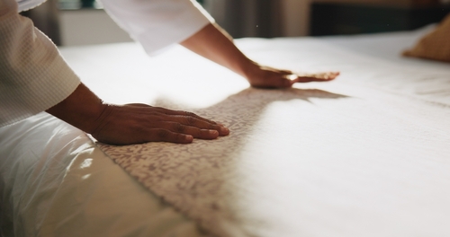 Guest’s hands pressing on hotel bed mattress, illustrating potential unsafe conditions investigated by a Daytona slip and fall accident lawyer.