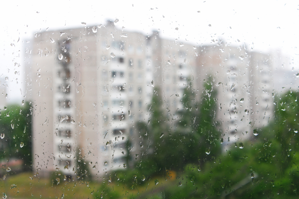 Rain-covered window overlooking apartment buildings, illustrating weather-related cases handled by a Gainesville Premises Liability Lawyer.