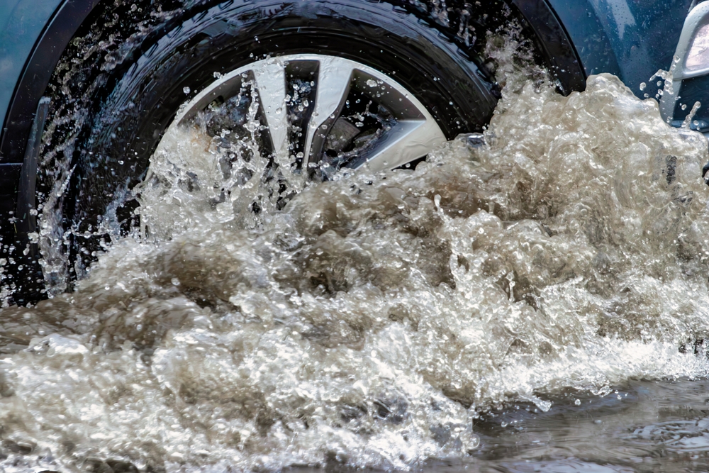 Gainesville car accident lawyer explains how rain and weather conditions affect vehicle control as a car drives through deep water on the road.