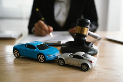 Gainesville car accident lawyer explains Florida comparative negligence law using model cars and a gavel to represent liability and fault.