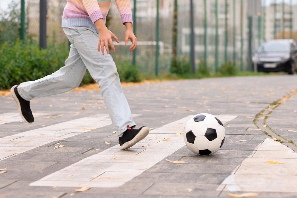 Child chasing a soccer ball across a Duckpond neighborhood crosswalk near a parked car in Gainesville