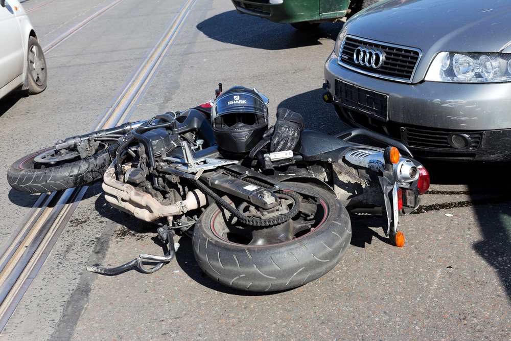 Motorcycle lying on the road next to a car after a motorcycle accident causing brain injury