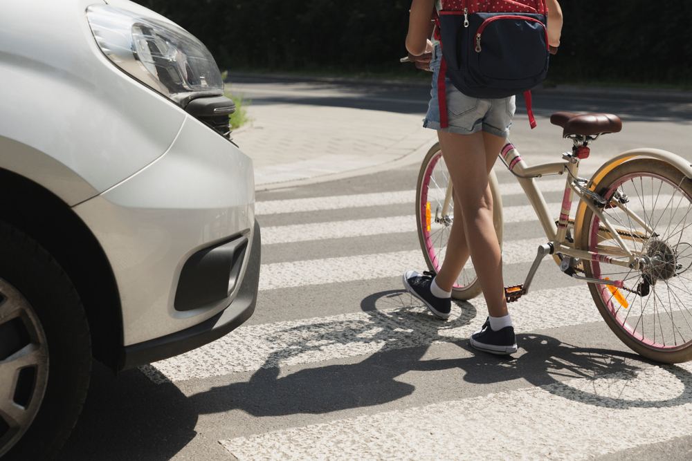 Child on a bicycle crossing at a crosswalk in front of a car in downtown Ocala