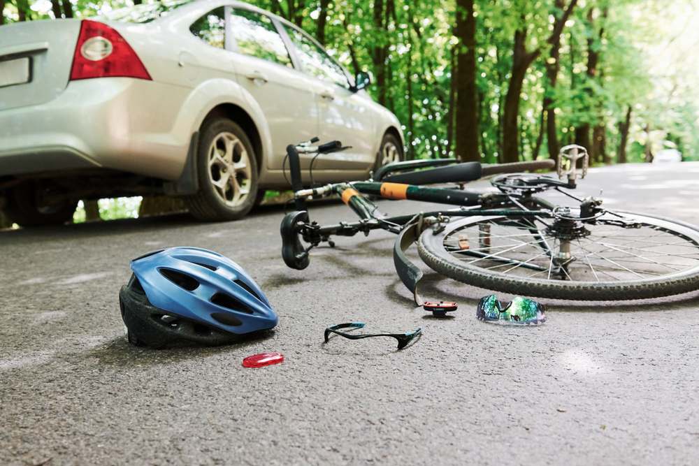 Bicycle scattered on the road next to a car after a bicycle accident near University Park
