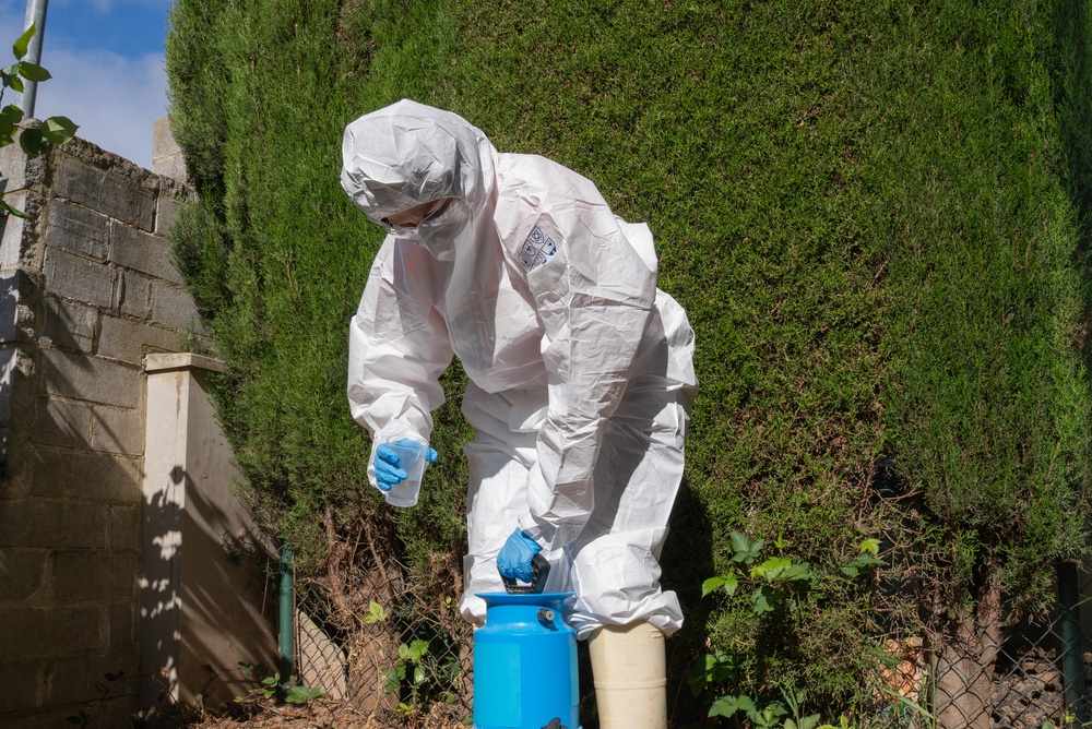 Worker in protective gear handling herbicide chemicals