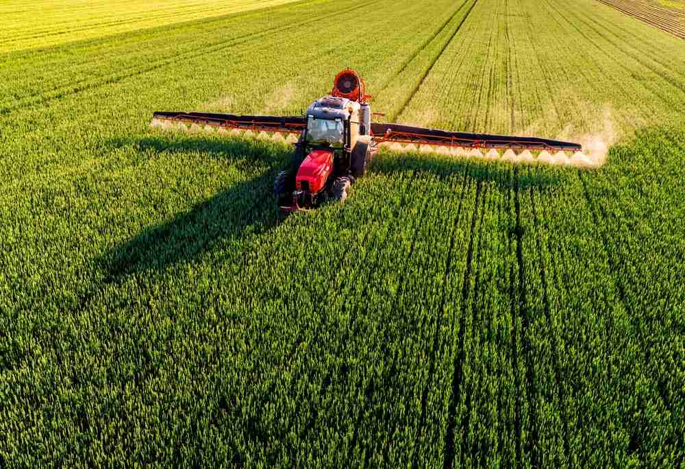 Tractor spraying herbicide across an agricultural field