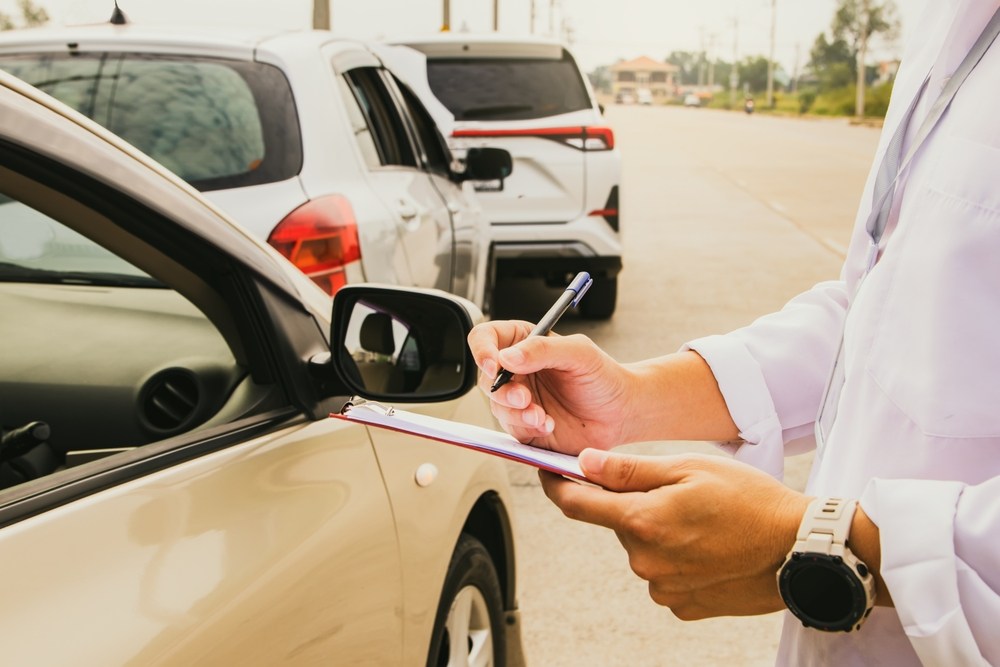 Insurance adjuster documenting vehicle damage after a crash