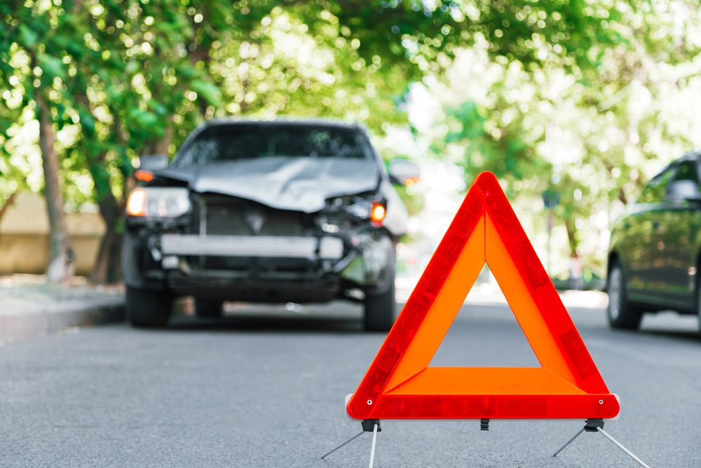 Warning triangle placed near a damaged vehicle after a Haile Plantation car accident