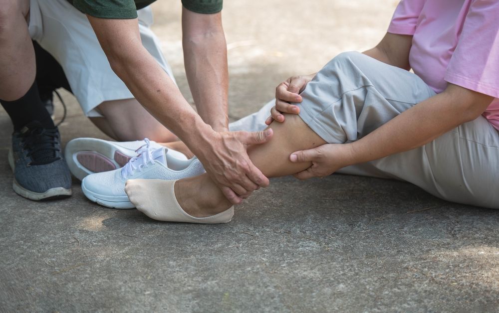 Man helping woman with leg injury after slip and fall accident on sidewalk in Ocala
