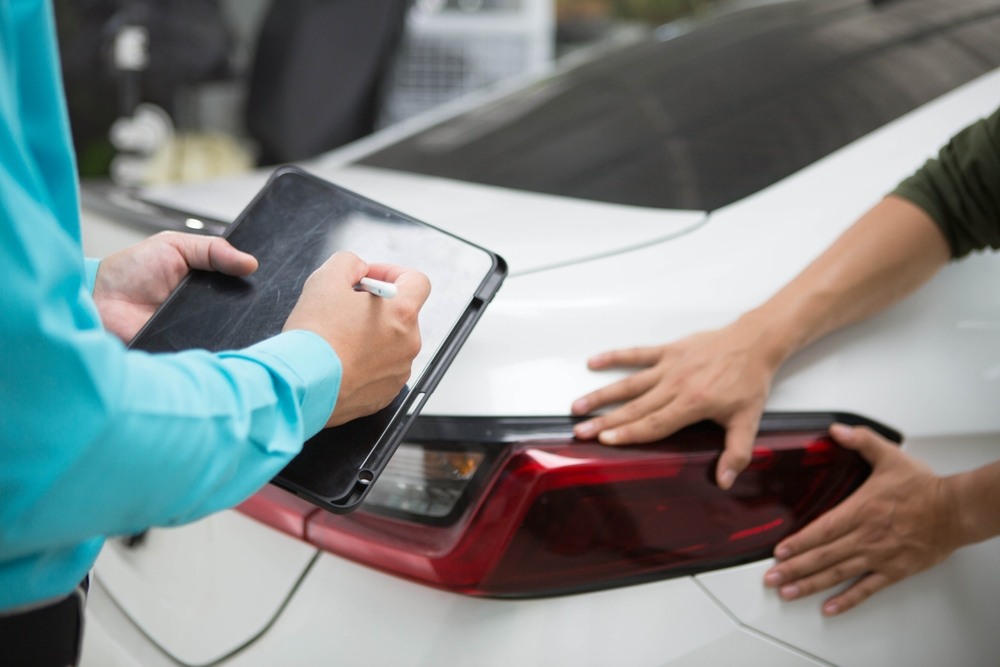 Adjuster inspecting vehicle damage for an uninsured motorist claim
